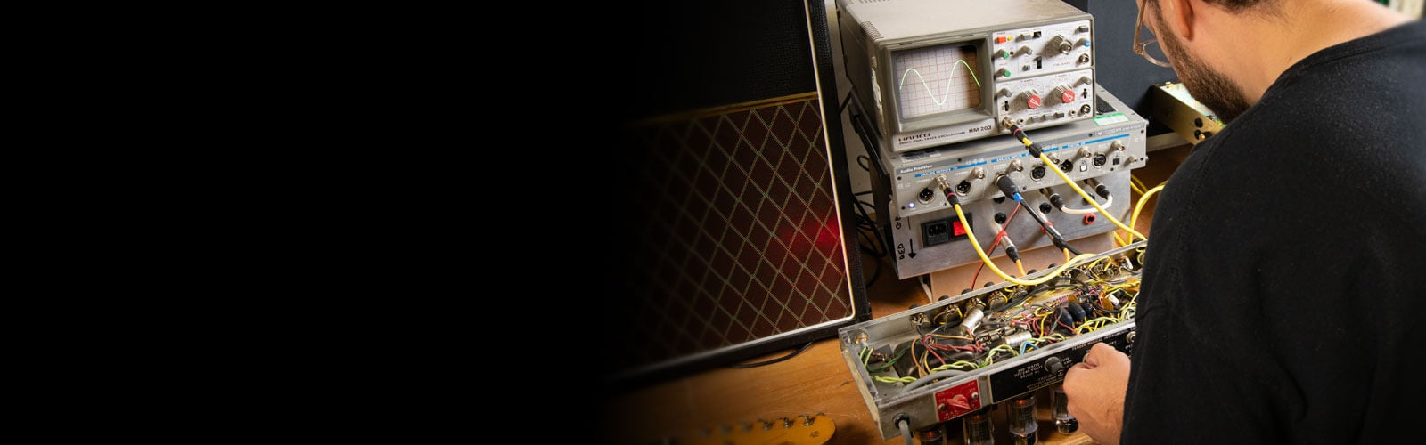 Ampton engineer working with the guts of classic amplifiers in a workshop setting